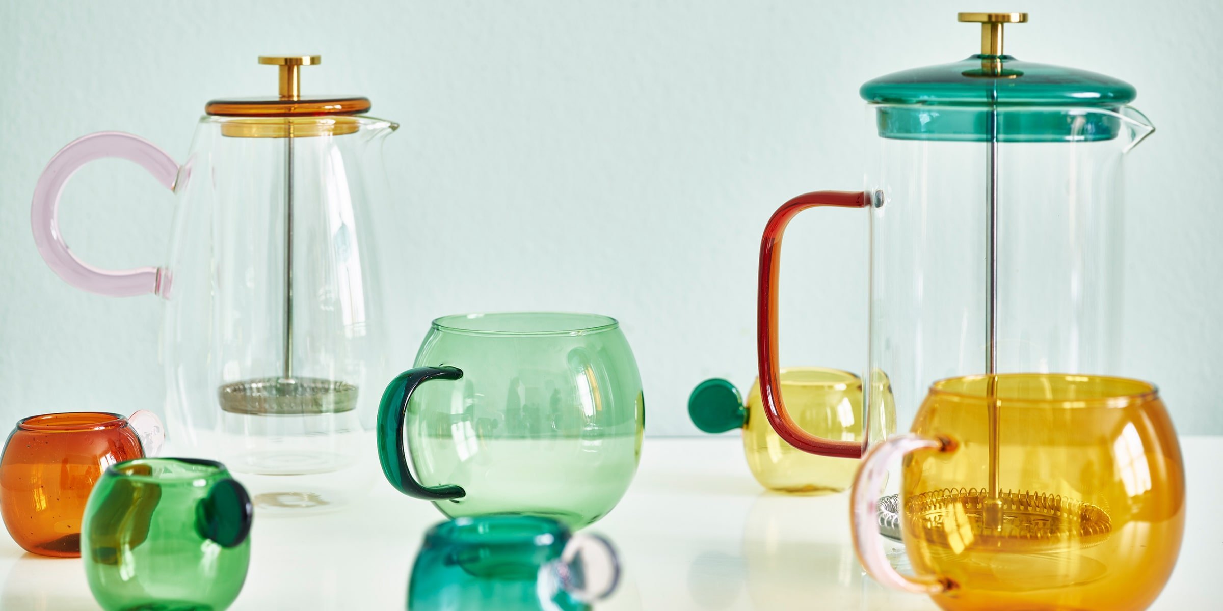A glass cafetiere and colourful coffee mugs