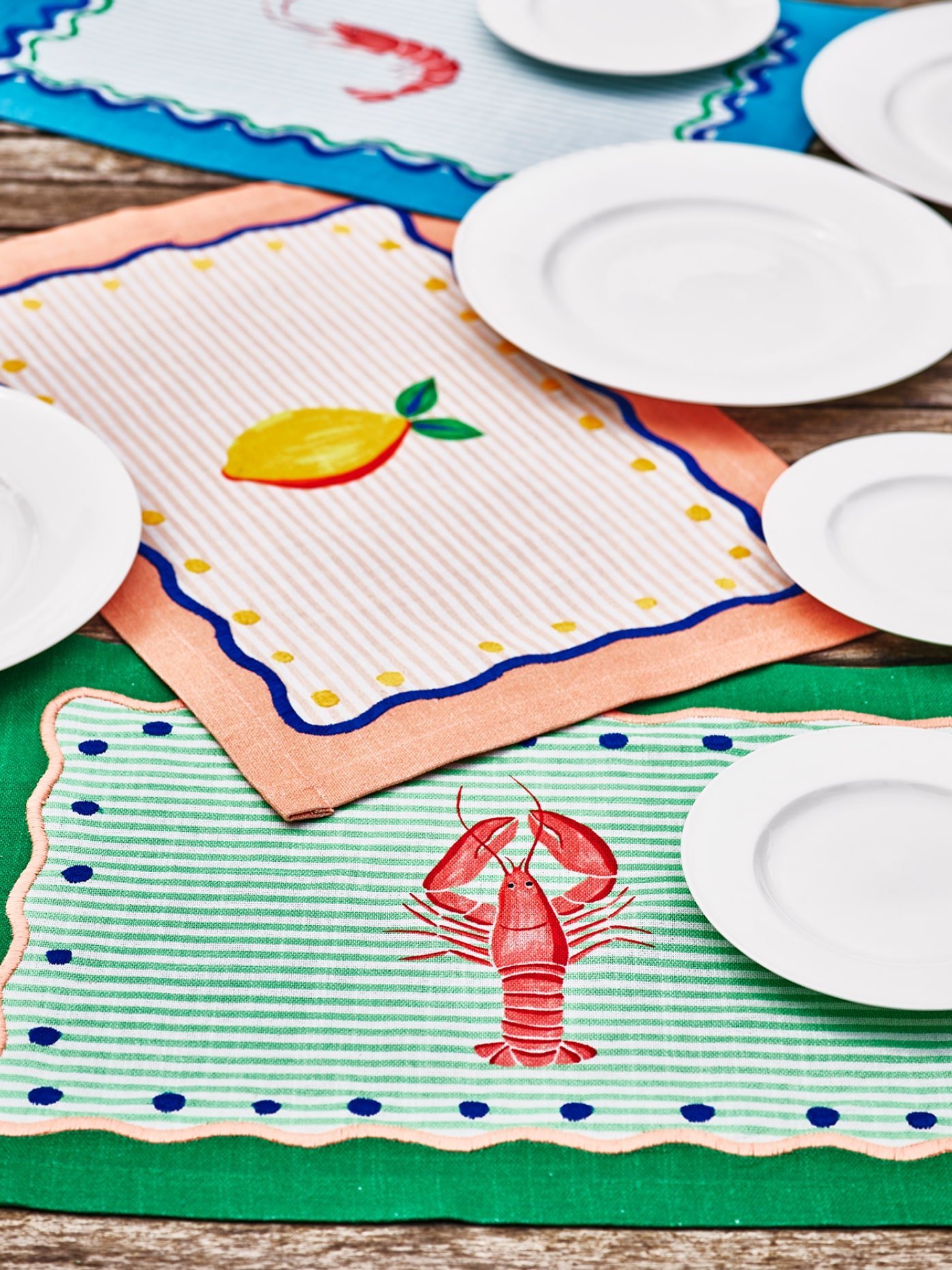 Colourful tea towels on a table with white plates