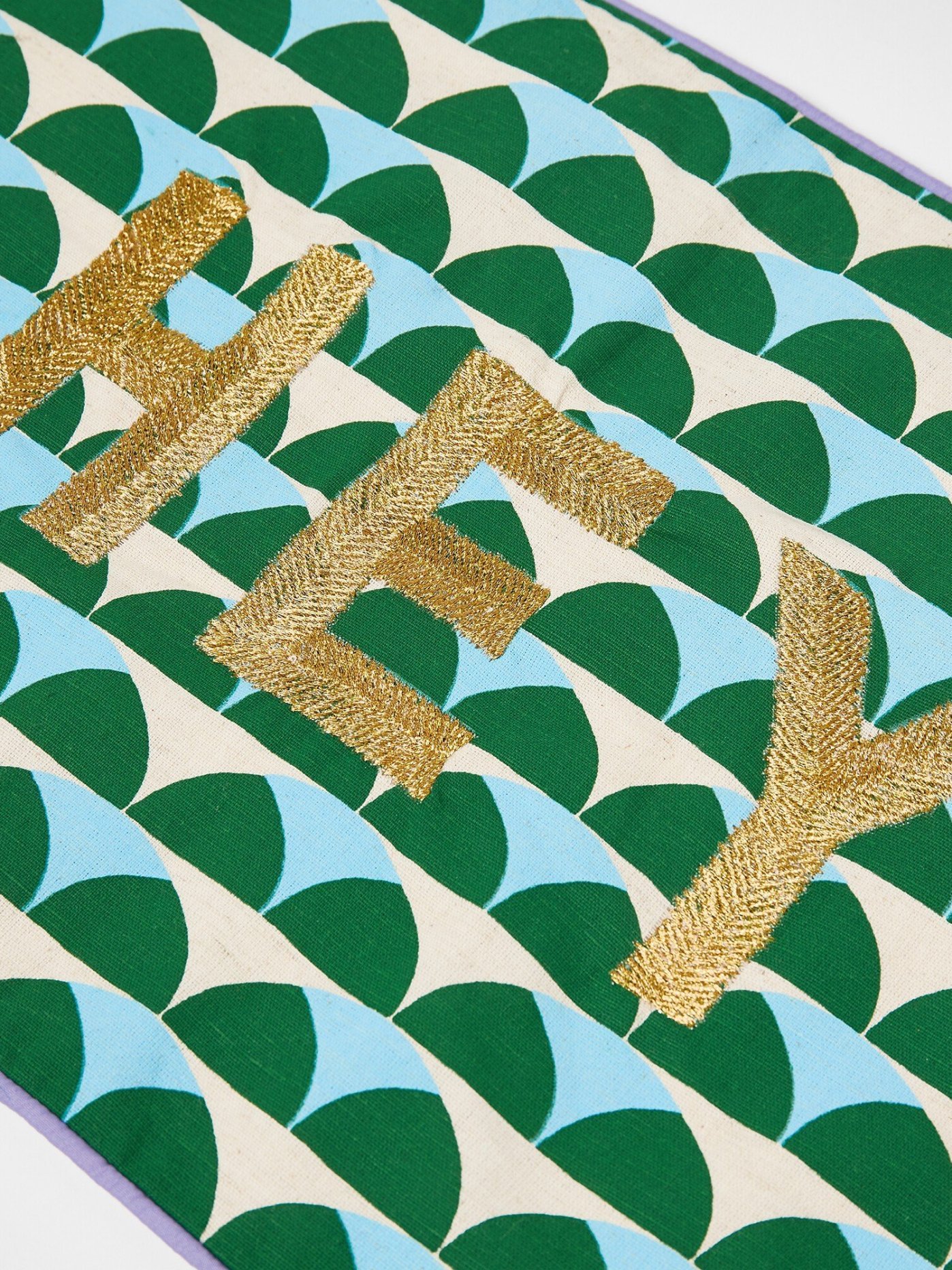 A green patterned cushion with ‘Hey’ on the front