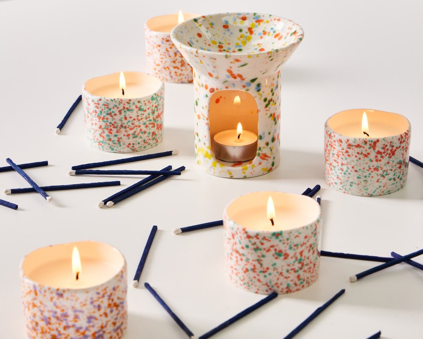 A group of ceramic splatter scented candles and matches