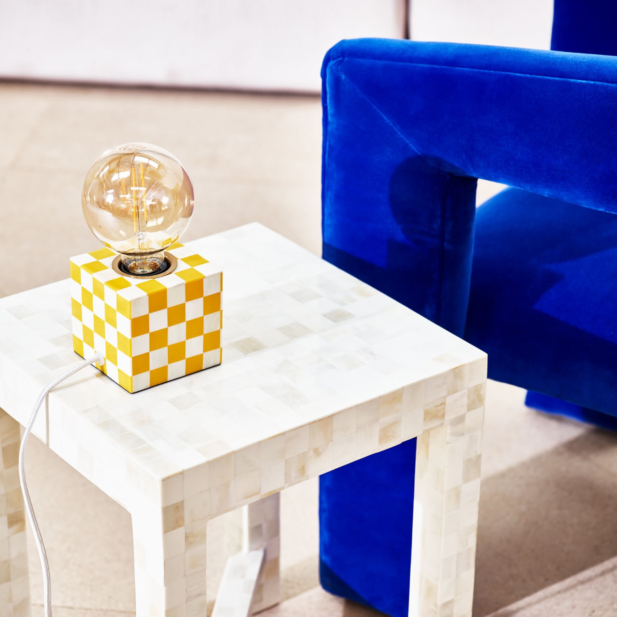 Chequerboard lamp base on a white side table  