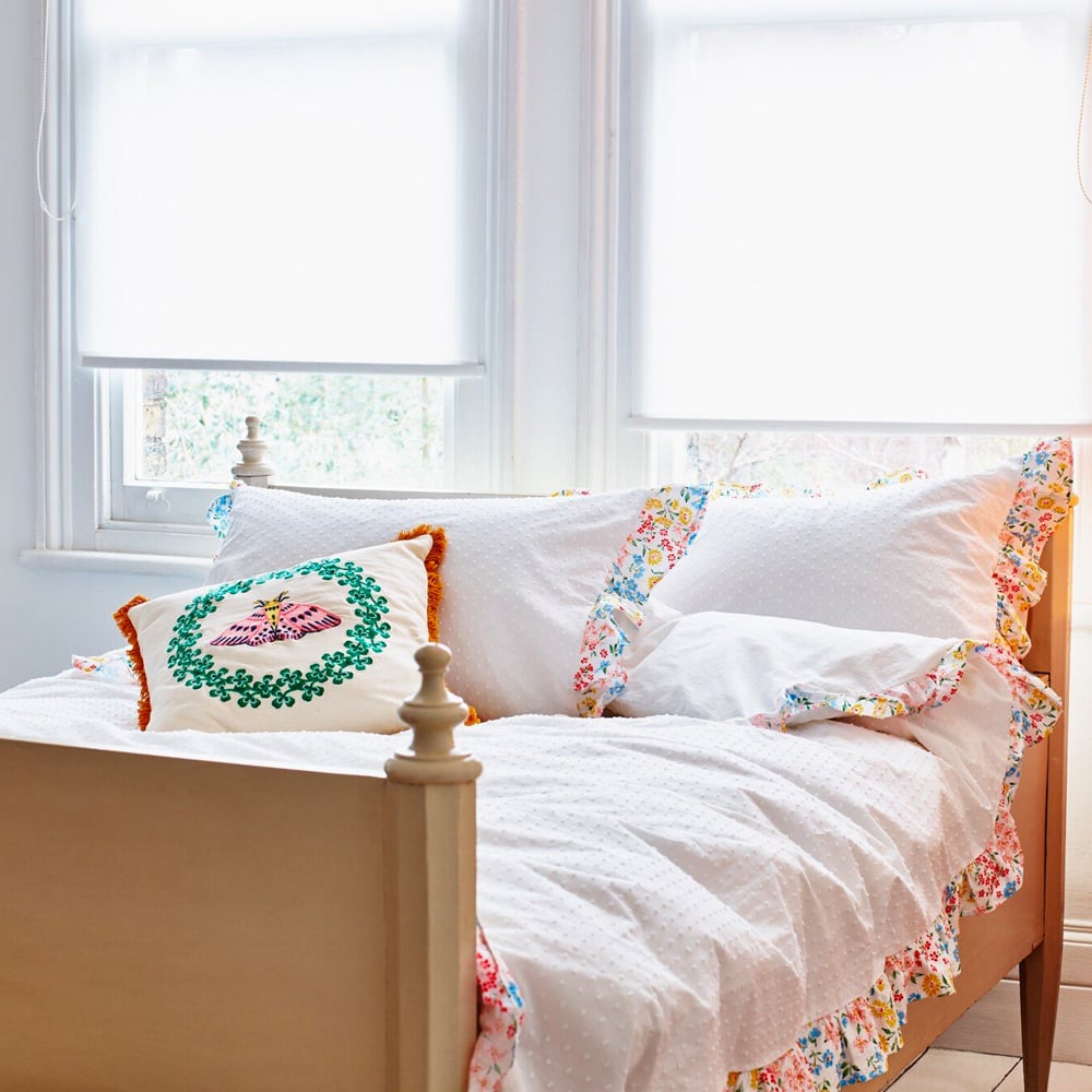 A bed with white frilly bed set 