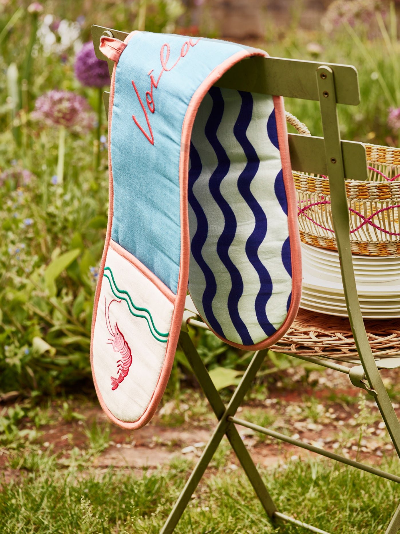Blue oven gloves on a green metal chair in a garden